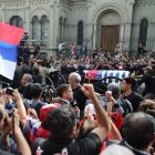 Personas asisten al cortejo fúnebre.