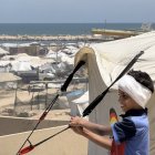 Un niño con la cabeza vendada juega junto a unas tiendas de refugiados en Gaza.