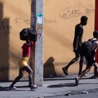 Fotografía de archivo del 23 de febrero de 2025 de tres personas caminando con sus pertenencias en Puerto Príncipe (Haiti). EFE/ Mentor David Lorens.