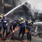Bombreos apagan el fuego del avión que cayó sobre una residencia de estudiantes.