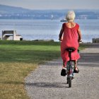 Una mujer mayor pasea en bicicleta cerca de la playa.
