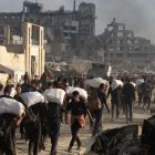 Desplazados palestinos llevan paquetes de ayuda humanitaria a lo largo de la calle Rashid, al oeste de Yabalia, el 22 de junio . EFE/EPA/HAITHAM IMAD.