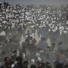 Cientos de palestinos desplazados cargan sacos de harina cerca de un punto de distribución de alimentos en Zikim, al norte de la Franja de Gaza.