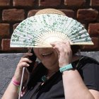 Una mujer se protege del sol con un abanico.