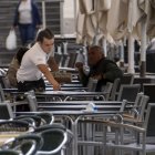 Un camarero prepara una de las mesas de la terraza.