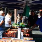 Un productor exhibe muestra sus tomates a los compradores.