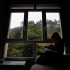 Un niño en libro al lado de la ventana.