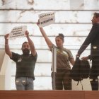 Dos bomberos forestales muestran pancartas durante el  Pleno extraordinario de las Cortes.