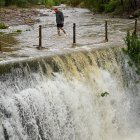 Un hombre cruza un badén inundable durante este lunes en Castellón.