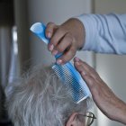 Una cuidadora peina a una persona dependiente.