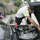 Un migrante arregla un coche.
