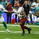 Un jugador de los Washington Commanders con el balón ante varios rivales de los Miami Dolphins, durante el partido de liga regular de la Liga de Fútbol Americano (NFL), que este domingo disputan en el Santiago Bernabéu.