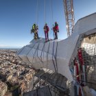 Varios operarios supervisan la construcción desde las alturas.