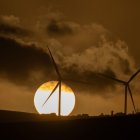 El sol se pone tras unos aerogeneradores durante el atardecer.