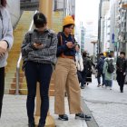 Dos jóvenes pendientes del teléfono móvil en una ciudad en Japón.