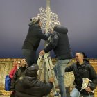 Los vecinos colacan una de las estrellas que han realizado con perchas.