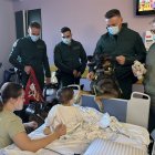Agentes de la Guardia Civil, con el presidente de la Aecc, muestran el perro adiestrado a un niño ingresado en el Caule.