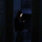 Un joven consulta su teléfono móvil en un balcón de Barcelona durante el apagón. EFE/Alberto Estévez.