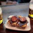 Tapa clásica de cecina y chorizo dulce que acompaña la caña en el Bar Entrepeñas, una experiencia de sabor leonés en pleno Barrio Húmedo.