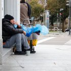 Un transeúnte, sentado en un umbral en una acera de León capital.