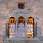 Detalle de la fachada histórica del Palacio del Conde Luna, donde la piedra medieval y la luz cálida del interior refuerzan la atmósfera legendaria del edificio.