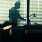 Imagen del documental Crímenes (Movistar Plus+) que recrea una escena de investigación, con dos personas en sombra tras unas persianas en un despacho