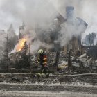 Un bombero pasa ante una casa atacada por Rusia en la región de Kiev.