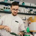 Un trabajador atiende el servicio del bar en temporada de verano, preparando una bebida refrescante para los usuarios de la piscina.