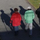 Tres personas mayores pasea por el río Bernesga en León.