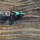 Un tractor pasa por unas hileras de paja sobrante tras la recolección de cereal.