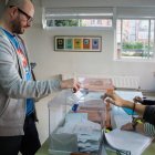 Un ciudadano introduce su voto en la urna ante la supervisión de los miembros de la mesa durante una jornada electoral en un colegio electoral.