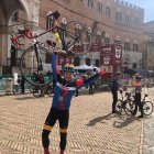 Alberto Viejo Escudero 'Albertín' levanta su bicicleta tras completar la Strade Bianche en 2023.