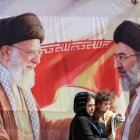 Una mujer pasa junto a una valla con Jamenei y a su hijo, el líder supremo iraní.