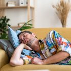 Un hombre se echa una siesta en el sofá de su casa