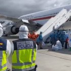 Los pasajeros españoles, con trajes epi blancos auxiliados por militares con epi naranjas, suben al avión del Ejército rumbo al Gómez Ulla.