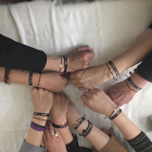 Un grupo de mujeres de la Semana Santa de León juntas sus manos en una señal de apoyo mútuo y fuerza.