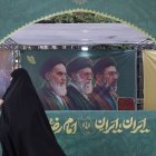Una mujer pasa delante de un cartel en Teherán que muestra a los líderes de la República Islámica, incluido Mojtaba Jameneí.