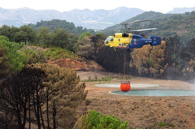 Un helicóptero carga agua para refrescar la zona incendiada. DANIEL PÉREZ