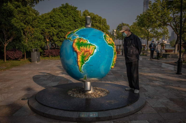 Un hombre observa una bola del mundo en Wuhan. ROMA PHILIPPEY
