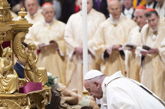El papa besa los pies a la figura del niño Jesús, ayer.