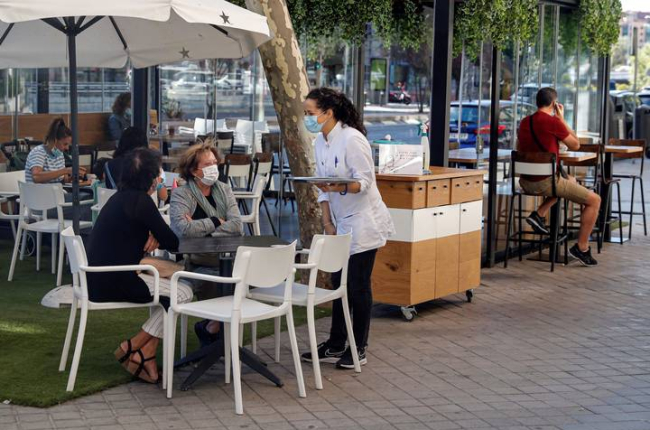 Varias personas en una terraza de un bar de Madrid, atendidos por una camarera. EMILIO NARANJO