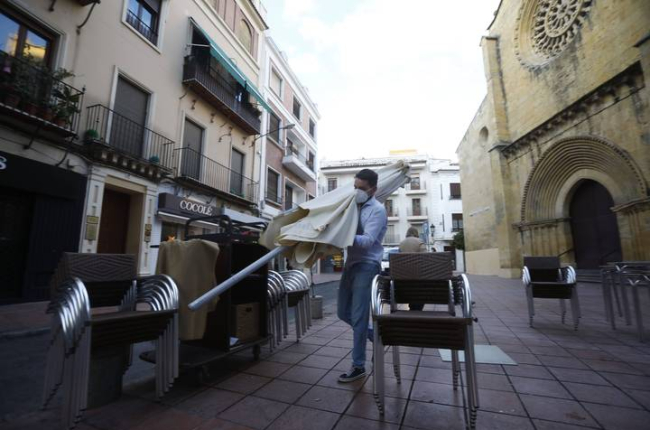 Un trabajador recoge el mobiliario de la terraza de un restaurante en el centro de Córdoba, ayer, cuando entraron en vigor las nuevas restricciones en Andalucía. SALAS