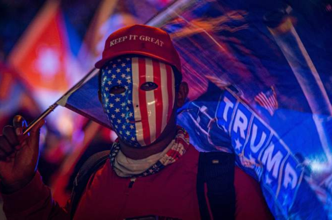 Un simpatizante de Donald Trump viste careta con la bandera estadounidense y una gorra que dice «Mantén (América) grandiosa» en Miami. GIORGIO VIERA