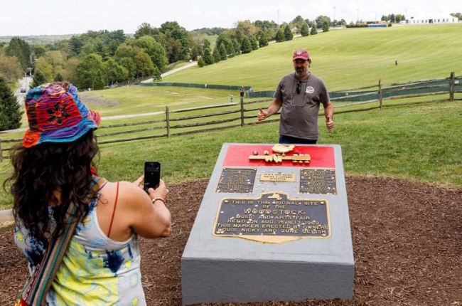 Turistas posan delante de la placa conmemorativa del festival de Woodstock en la localidad de Bethel (Nueva York, Estados Unidos). JUSTIN LANE