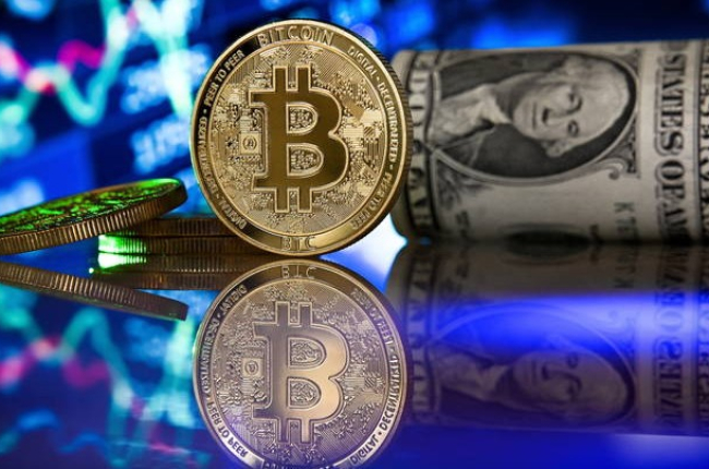 Fotografía de archivo fechada el 20 de enero de 2021 que muestra un bitcoin junto a un fajo de dólares. EFE
