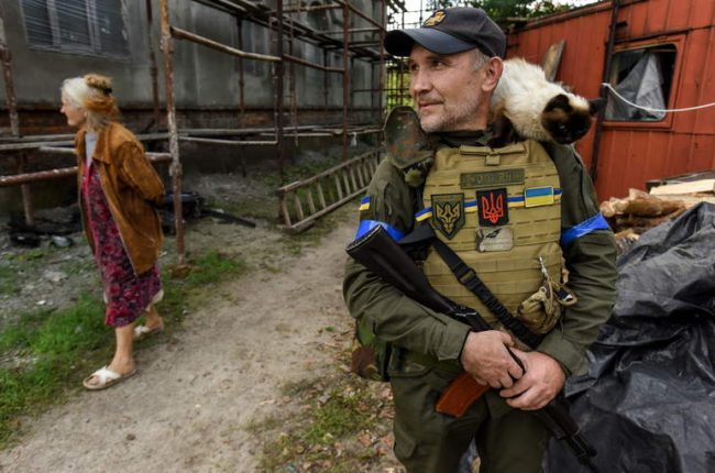 Una mujer pasa ante un miembro de la Guardia Nacional ucraniana. OLEG PETRASYUK