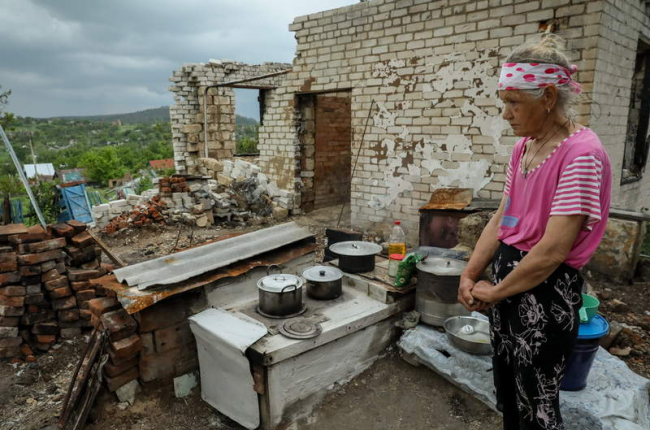 Una mujer cocina sobre los restos de su casa, destruida en el pueblo de Bohorodychne. OLEG PETRASYUK