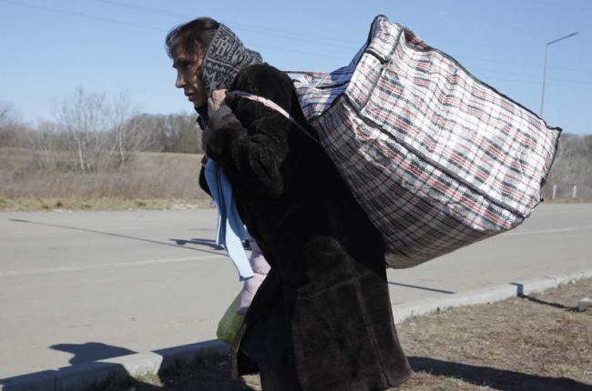 Una mujer ucraniana camina por la carretera con sus pertenencias en una bolsa. AMEL PAIN