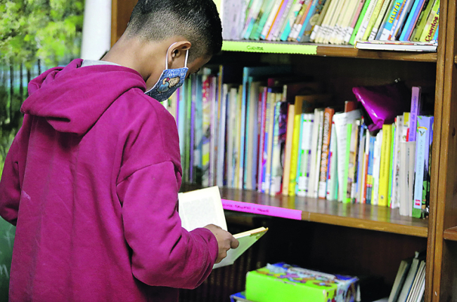 Uno de los alumnos consulta un libro en la biblioteca. RAMIRO