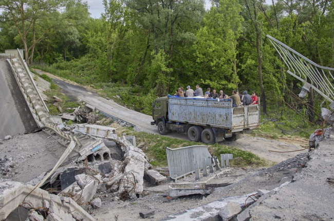 Un camión con civiles ucranianos cruza un puente improvisado construido junto a una estructura destruida en el área de Kharkiv. SERGEY KOZLOV